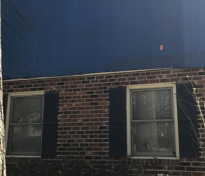 brick front wall of structure with blue tarp covering room 2 windows shown